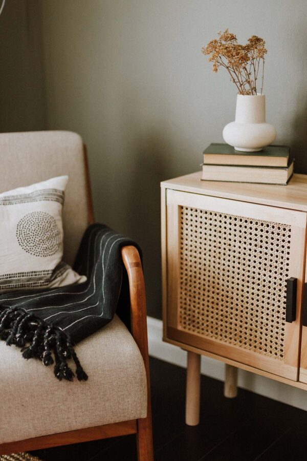 Seating area with plush chair and console with books and flowers.